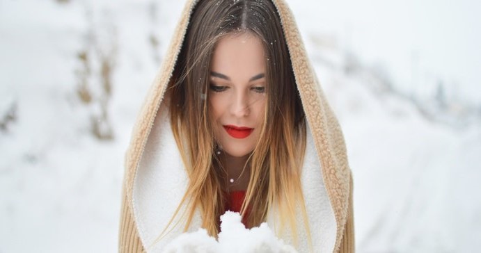 lady with red lips and a hood in the snow